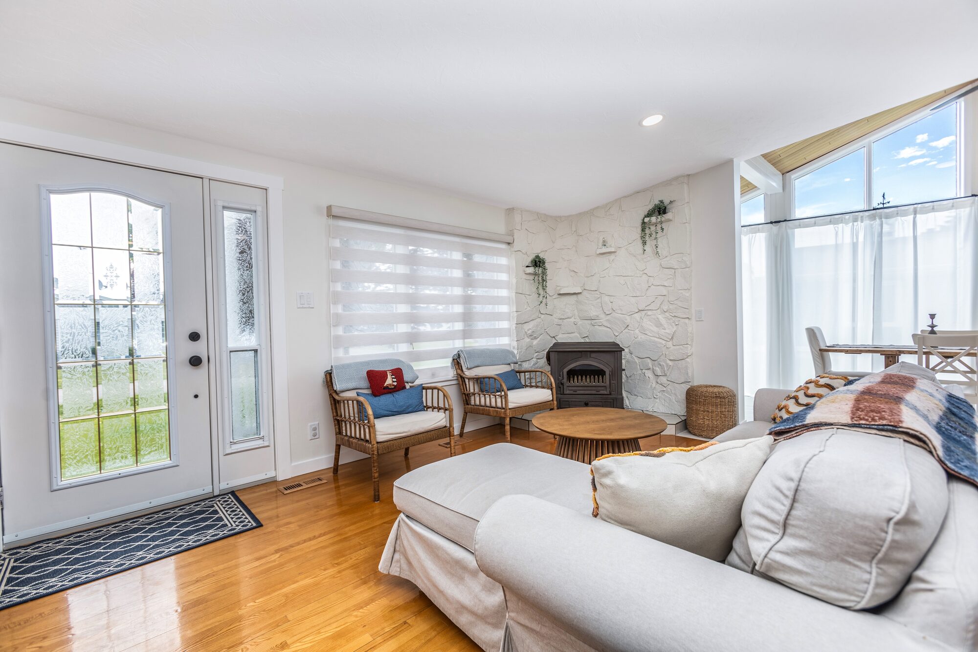 The living room with a slipcovered sofa, rattan chairs, and a stone hearth.
