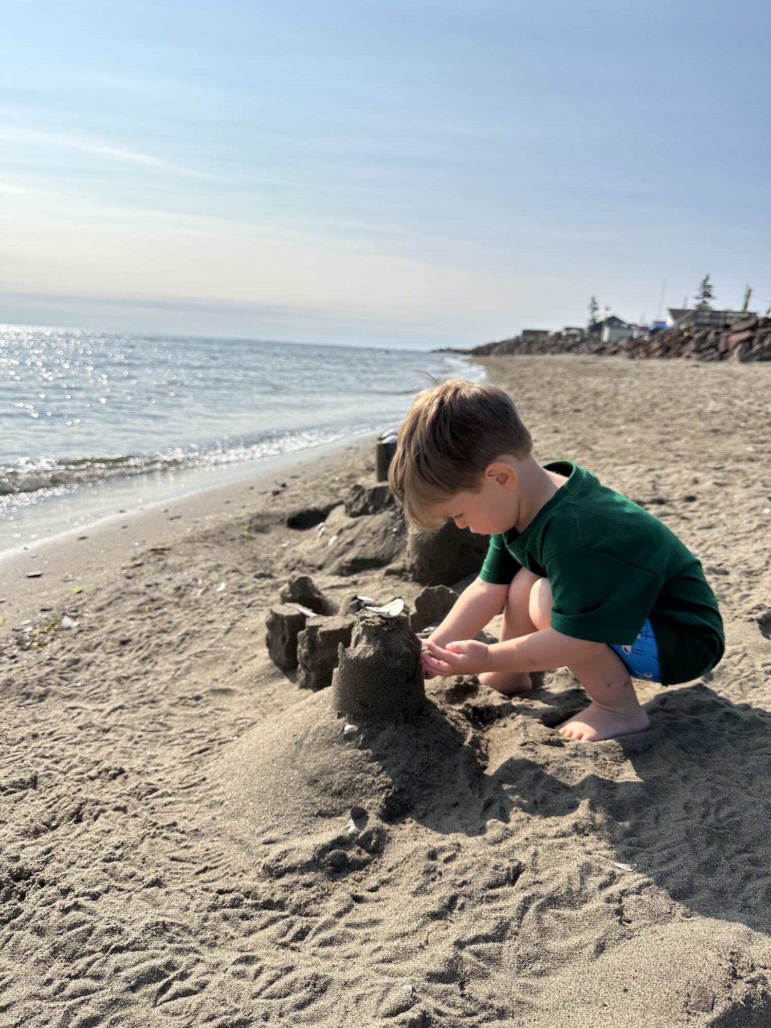 A small child building sandcastles by the warm-water shore.