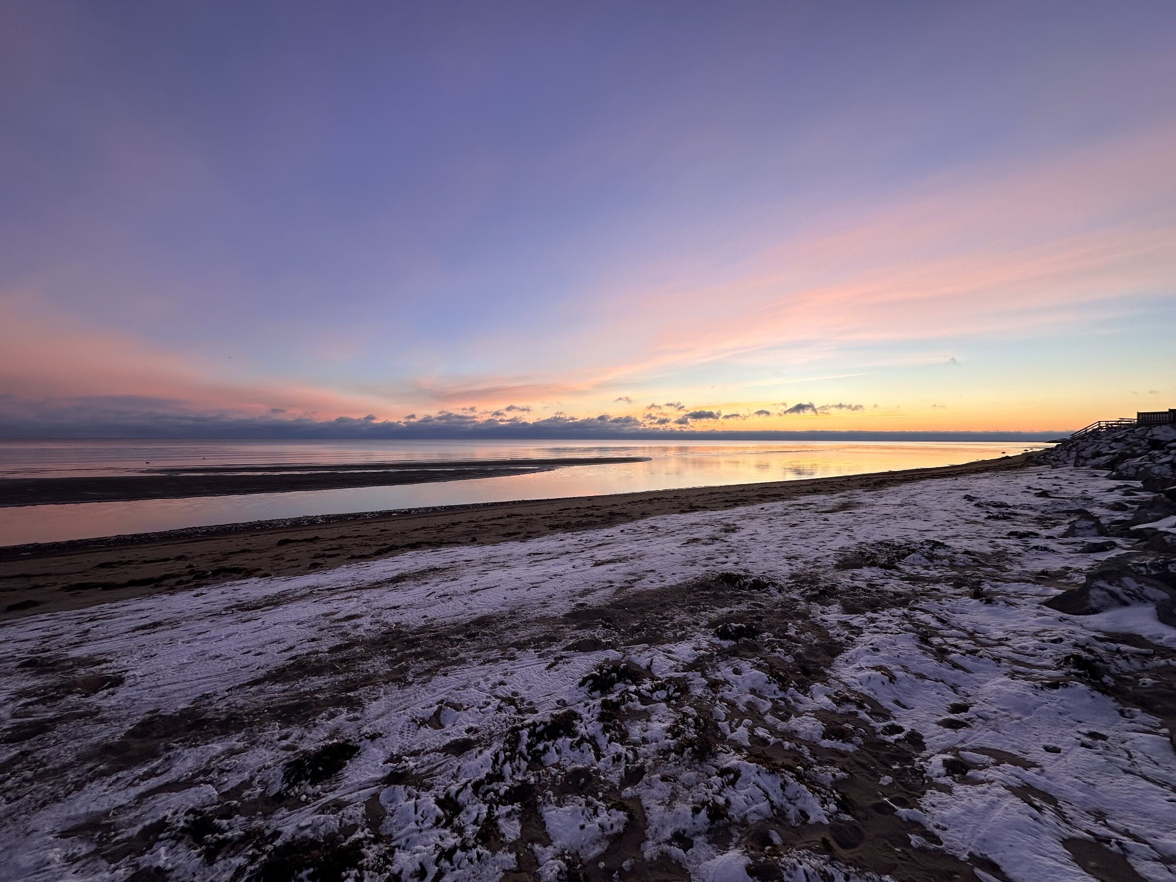 Pink and lavender winter sunrise over the snow-dusted shore of Cassie Cape.